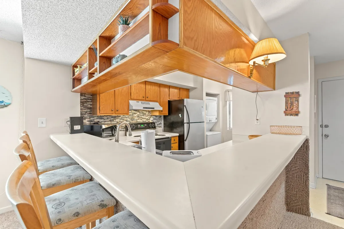 A spacious kitchen with a central island, bar stools, decorative shelving, and modern appliances. The space is set up for both cooking and casual dining, with a welcoming, functional design.