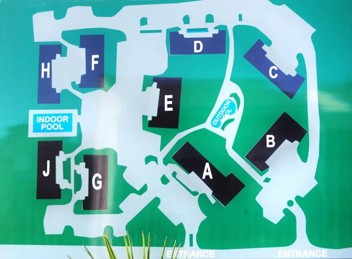 This image showcases both the indoor and outdoor resort pools surrounded by the Summertree Village buildings. The pools are inviting, with clear water and ample space, indicating a family-friendly environment ideal for swimming and relaxing together rain or shine.