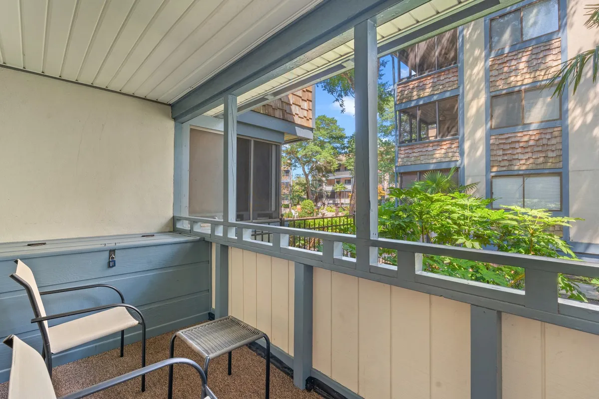 A peaceful balcony area featuring two comfortable chairs and a small table, with a view of a green plant just outside. The space is perfect for unwinding with a book, enjoying morning coffee, or relaxing while taking in the natural surroundings.